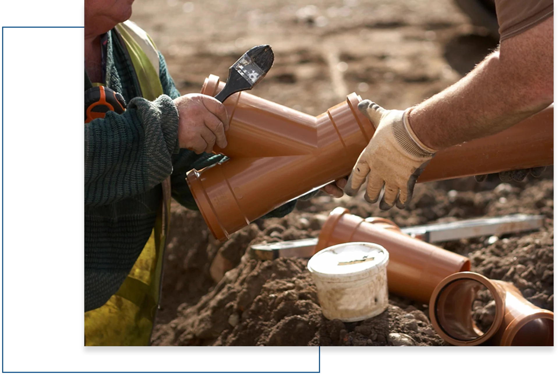 A person is holding a pipe while another person holds a tool.